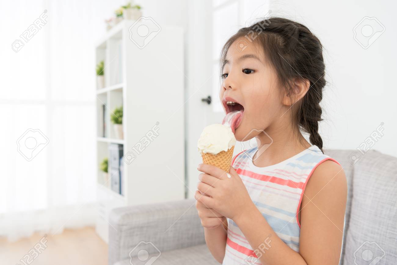 夏休みにアイスクリームを食べ 暑い日を楽しむリビングルームのソファでクールなデザートを舐める若いかわいい女性の子供たち の写真素材 画像素材 Image