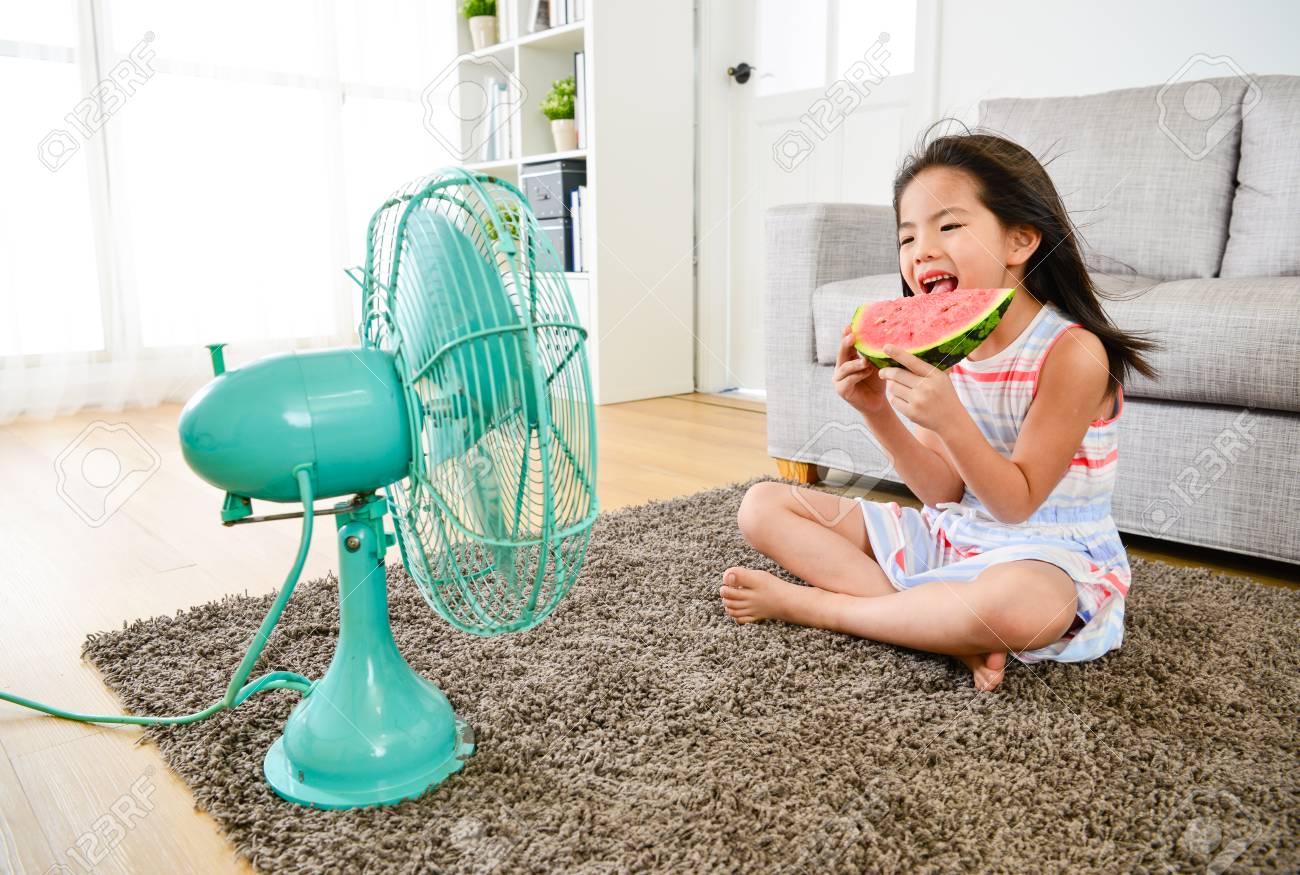 幸せなかわいい女の子の子供たちは 扇風機からの冷たい風を楽しみ 夏のシーズン中に新鮮なスイカを食べて 床に座っています の写真素材 画像素材 Image