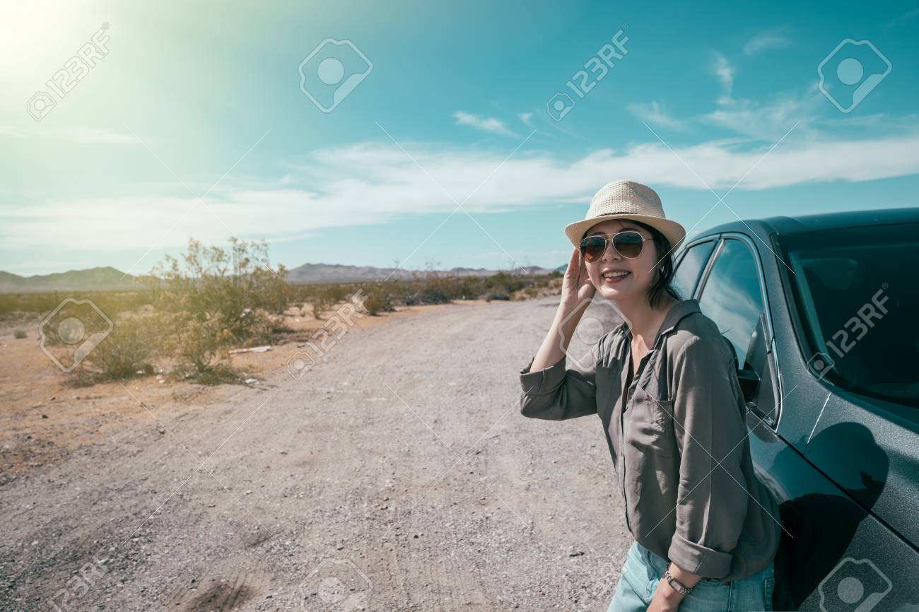 female car driver standing on the empty nature sunny day relying on the black car. young woman with straw hat and sunglasses enjoy the beauty of the wild during the trip. asian lady self driving tour - 112052296 female car driver standing on the empty nature sunny day relying on the black car. young woman with straw hat and sunglasses enjoy the beauty of the wild during the trip. asian lady self driving tour - 112052296