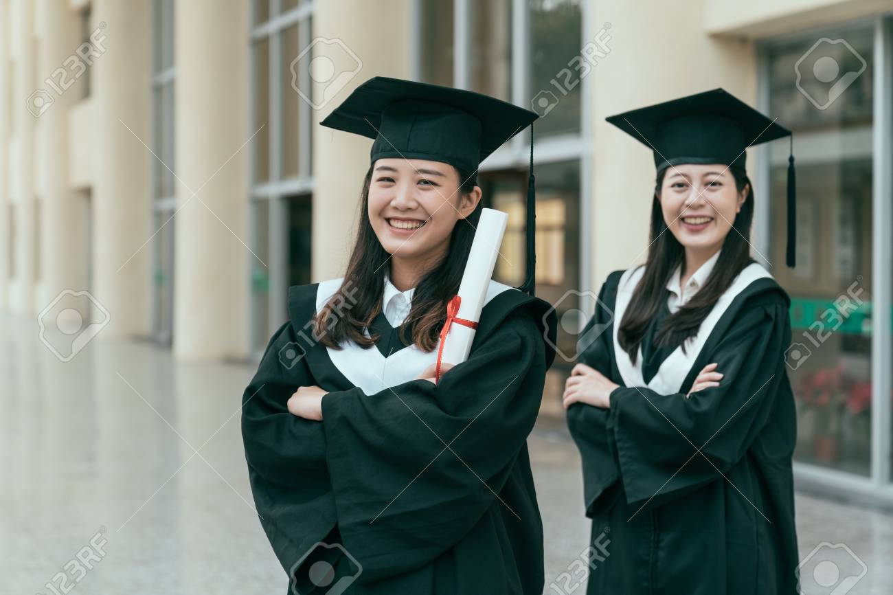 Two Asian Girls Standing In The Corridor Of University In Mantle. Glad  Graduate Students Crossed Arms Face Camera Holding Diploma Got Degree.  Confident Woman Finished College Achievement Future Trend. Stock Photo,  Picture, image size:1300x866