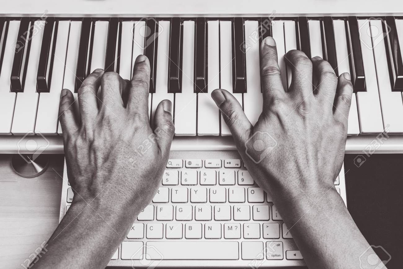 composer hands working on piano keys computer keyboard music production keys