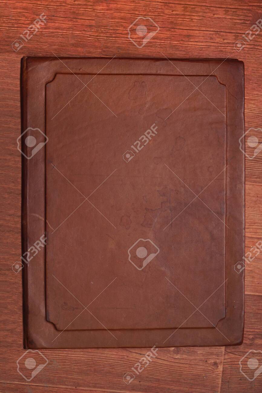 Antique brown aged leather cover with different spots on a wooden brown background - 145073254 Antique brown aged leather cover with different spots on a wooden brown background - 145073254