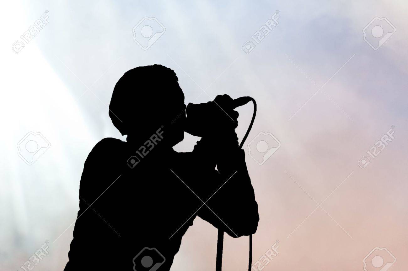 横のシルエットで彼の唇にマイクを持っている単一の歌手 の写真素材 画像素材 Image