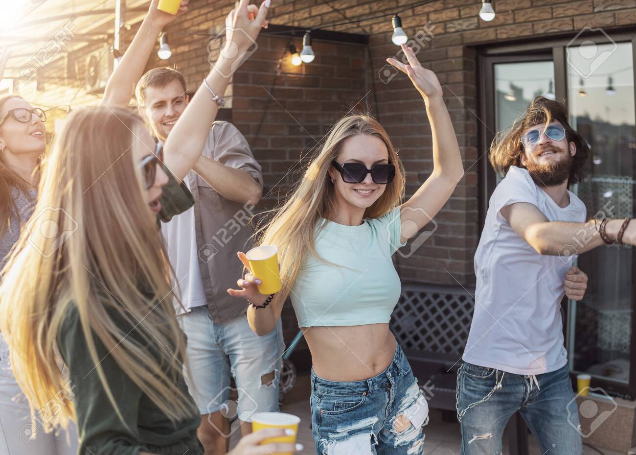 Youngsters have a dancing break during their party on a loft terrace - 145147735 Youngsters have a dancing break during their party on a loft terrace - 145147735