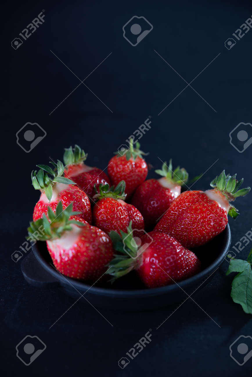 Fresh juicy strawberries in a black plate on a black matte background. - 154902150 Fresh juicy strawberries in a black plate on a black matte background. - 154902150