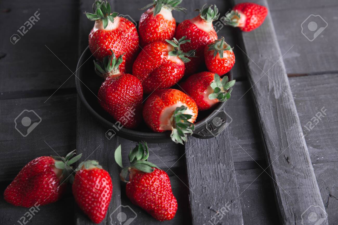 Fresh ripe strawberries on a black wooden background. - 154905664 Fresh ripe strawberries on a black wooden background. - 154905664