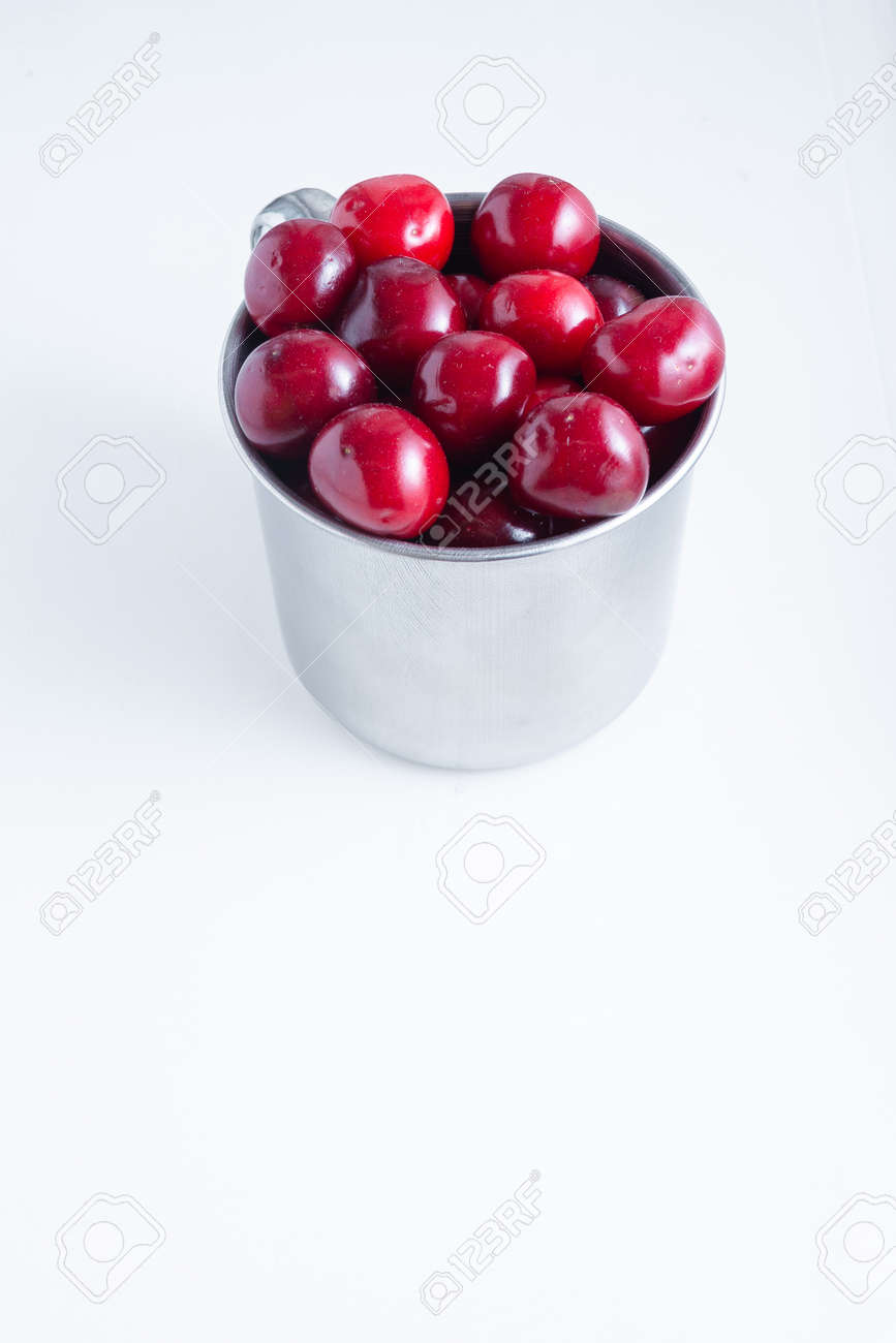 Sweet cherries in a steel mug on a white paper background. - 158020179 Sweet cherries in a steel mug on a white paper background. - 158020179