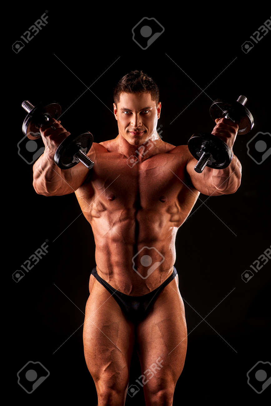 黒い背景の上にダンベル ポーズ ハンサムな筋肉ボディービルダーの肖像画 の写真素材 画像素材 Image