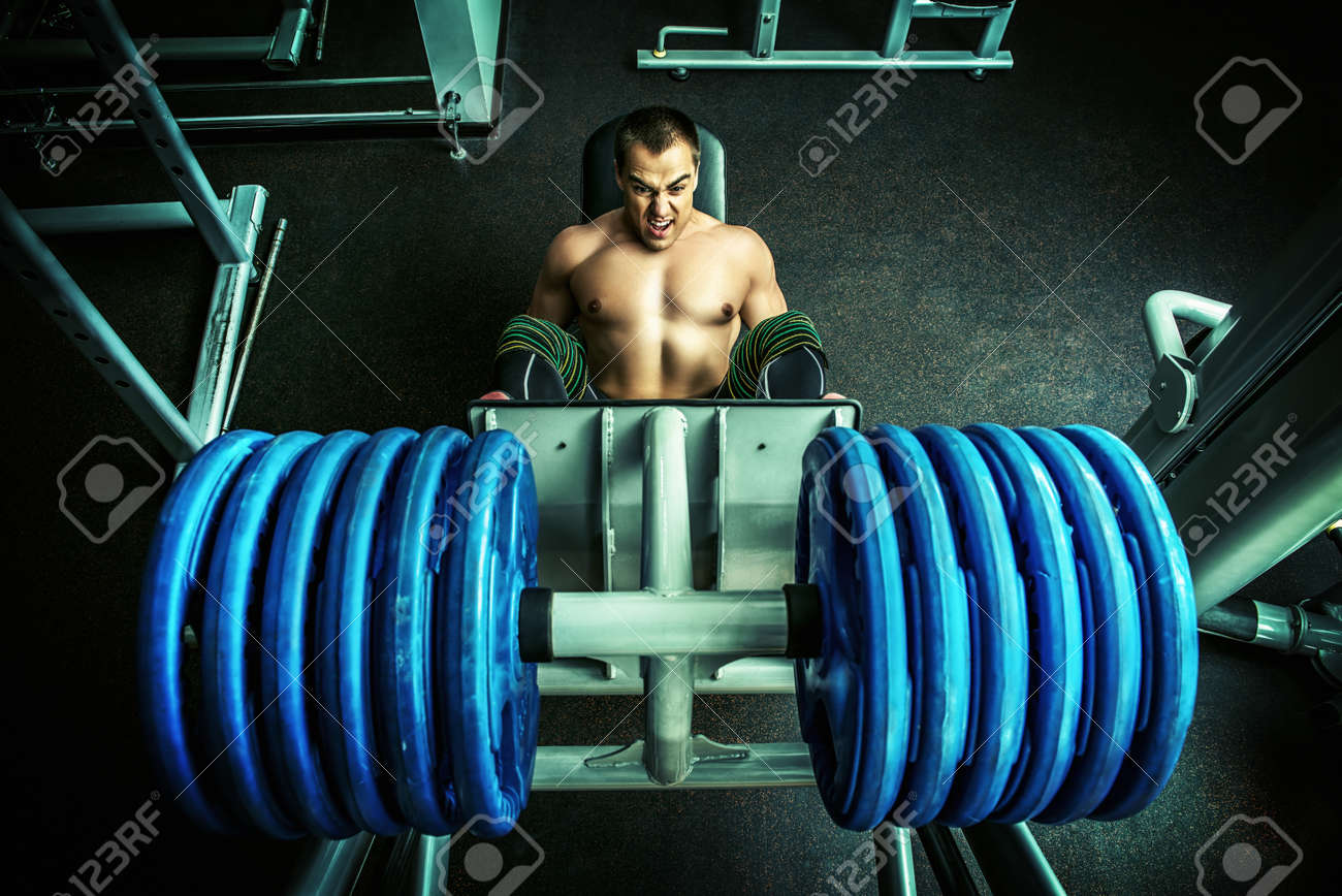 ジムで筋肉男重量挙げやって足を押した スポーツ の写真素材 画像