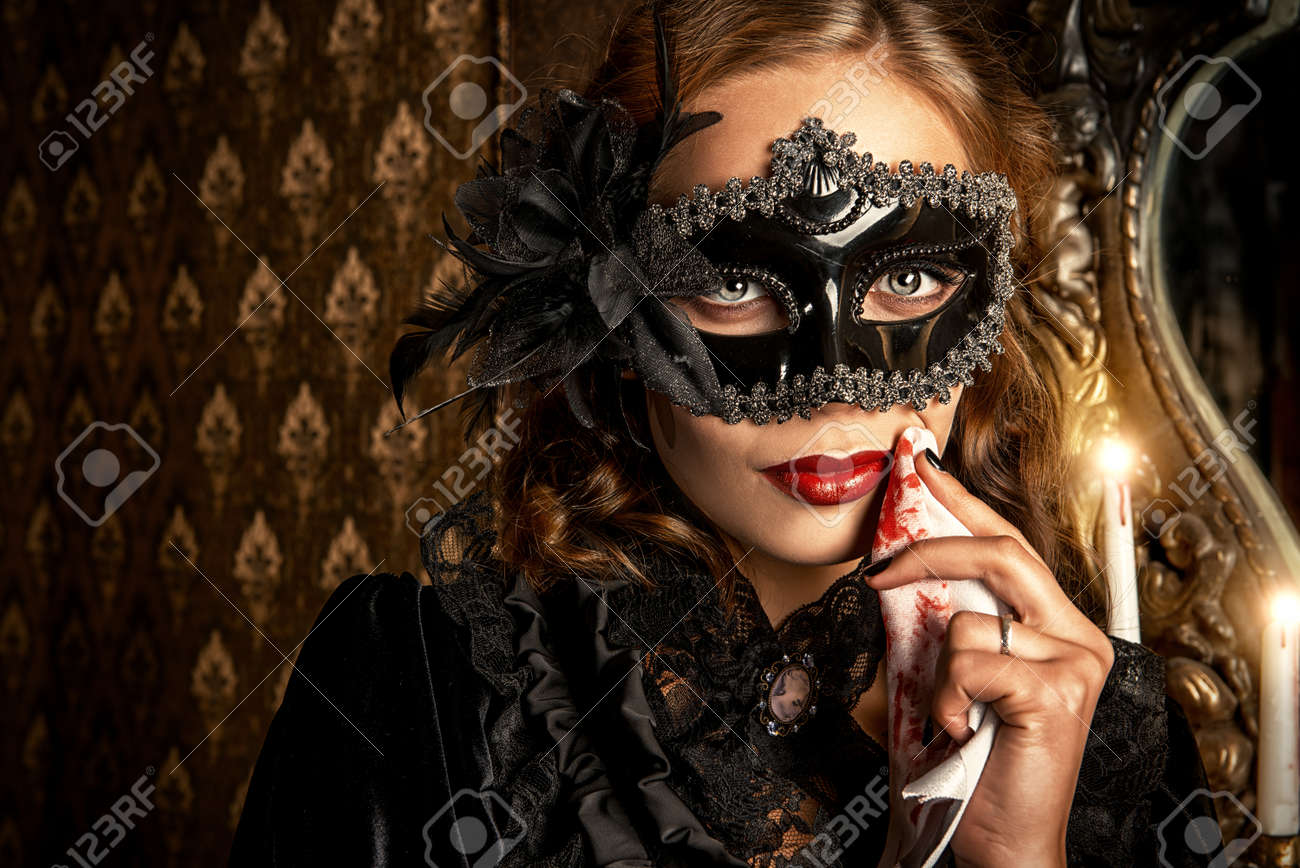 Charming mysterious girl in black mask and black medieval dress stands in a castle living room. Vampire. Halloween concept. Vintage style. - 50995790 Charming mysterious girl in black mask and black medieval dress stands in a castle living room. Vampire. Halloween concept. Vintage style. - 50995790