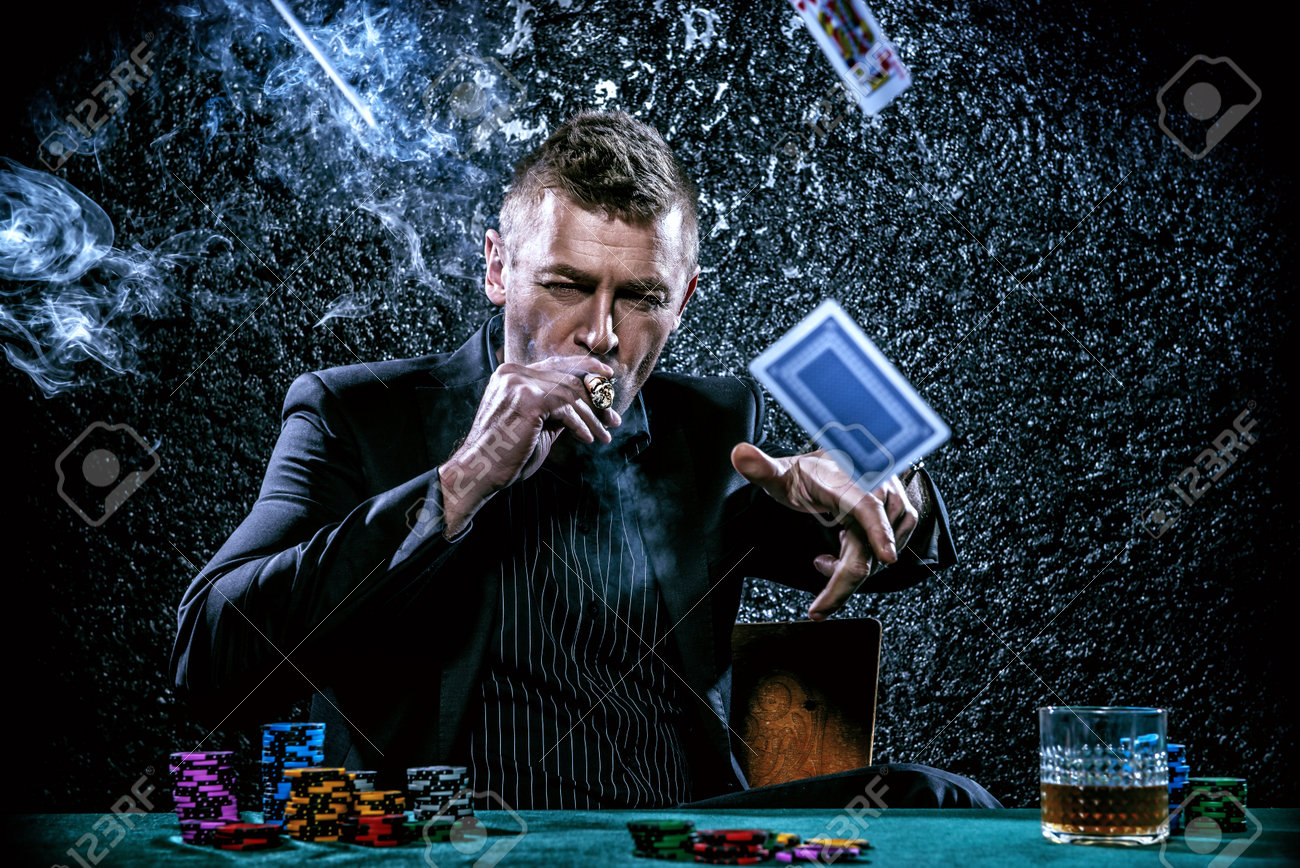 Excited gambling man throwing playing cards on a game table in a casino. Gambling, playing cards and roulette. - 67230547 Excited gambling man throwing playing cards on a game table in a casino. Gambling, playing cards and roulette. - 67230547