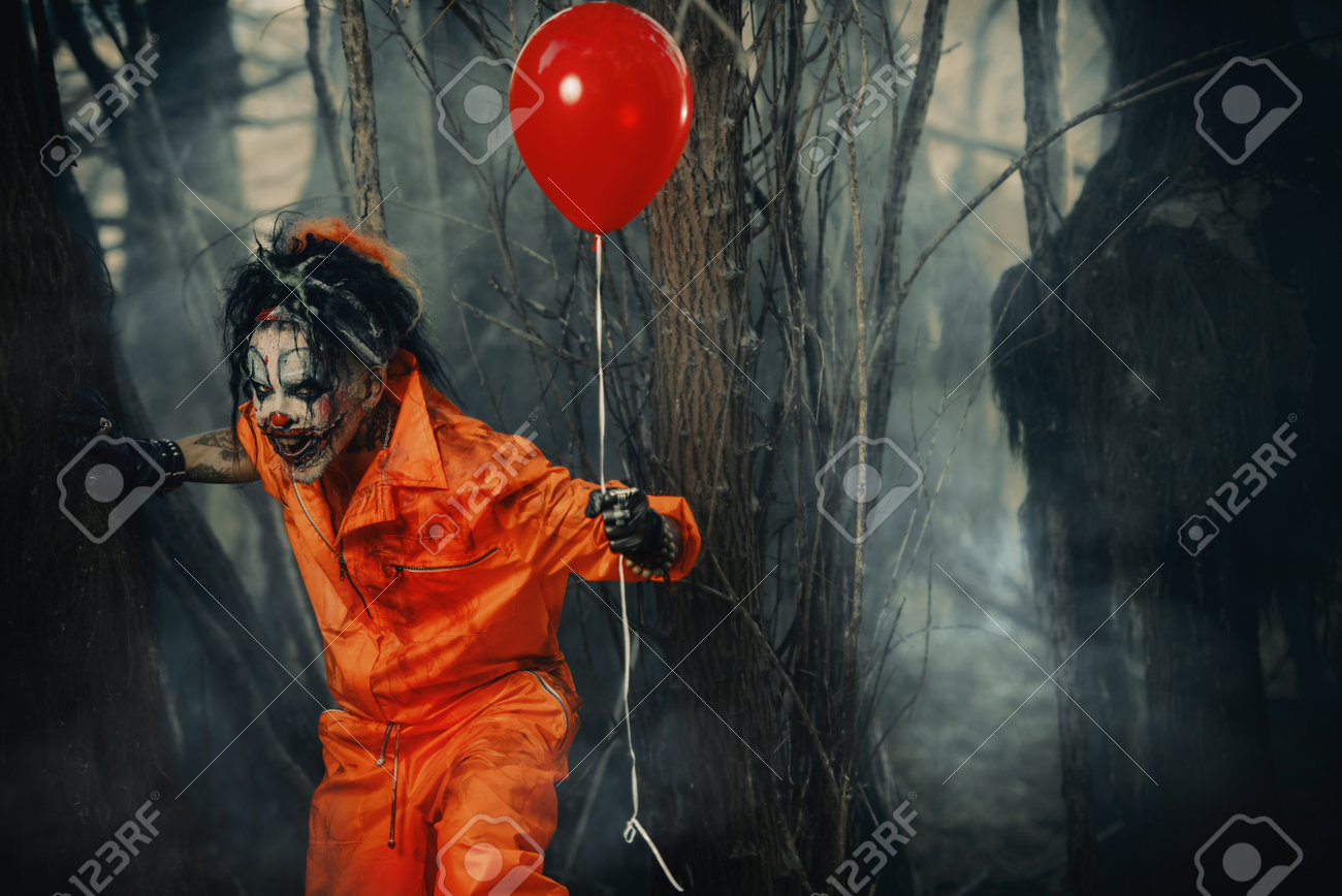 Scary man clown stained in blood in a night forest with a balloon. Male zombie clown. Halloween. Horror. - 85979148 Scary man clown stained in blood in a night forest with a balloon. Male zombie clown. Halloween. Horror. - 85979148