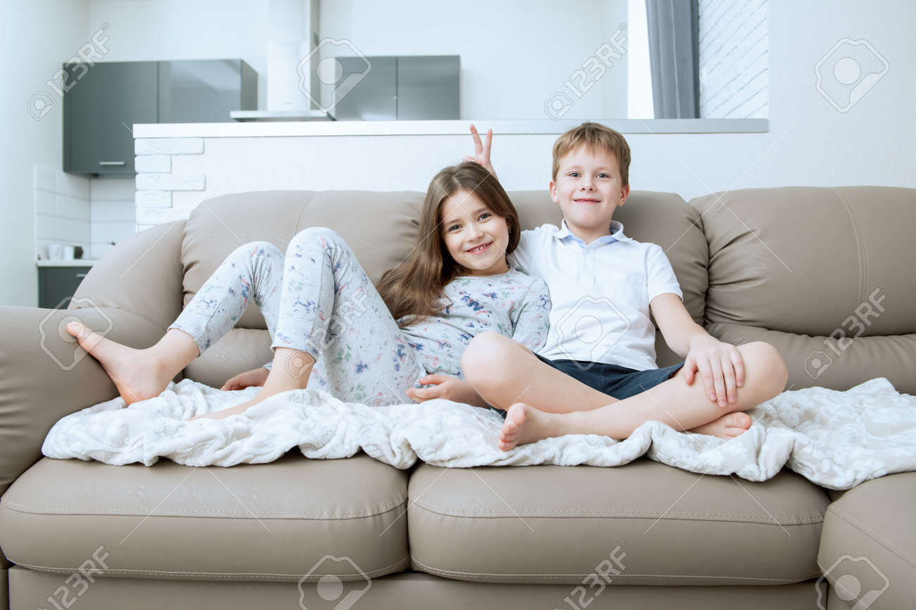 Cute boy and girl are sitting on the couch. Fashion home shot. Childhood. Kid's fashion. - 132931533 Cute boy and girl are sitting on the couch. Fashion home shot. Childhood. Kid's fashion. - 132931533