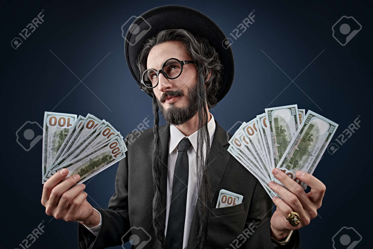 지폐 다발을 가진 부유한 유대인 남자의 초상화. 부유한 유태인 개념. 어두운 파란색 배경에서 촬영 스튜디오입니다. 로열티 무료 사진,  그림, 이미지 그리고 스톡포토그래피. Image 174717411
