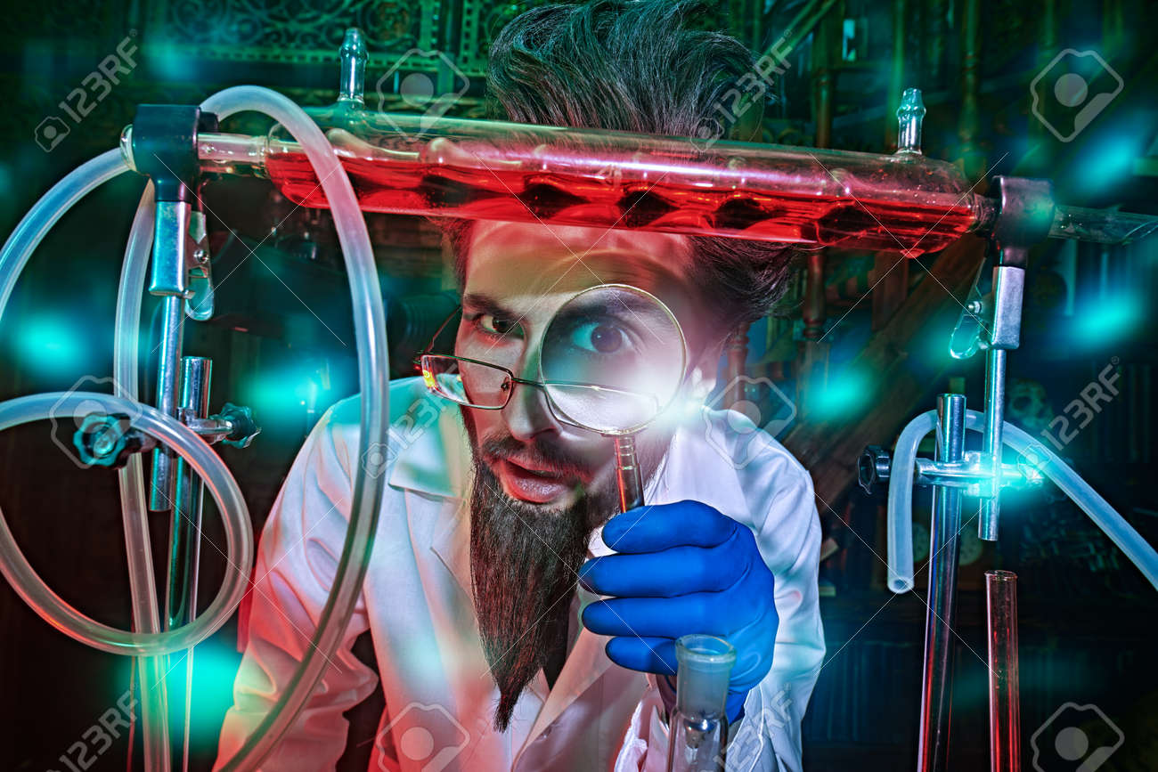 Portrait Of A Funny Mad Scientist Conducting Scientific Experiments In The  Laboratory And Looking At The Camera Through A Magnifying Glass. Fantasy,  Science Fiction Novel. Stock Photo, Picture and Royalty Free Image., image size:1300x867