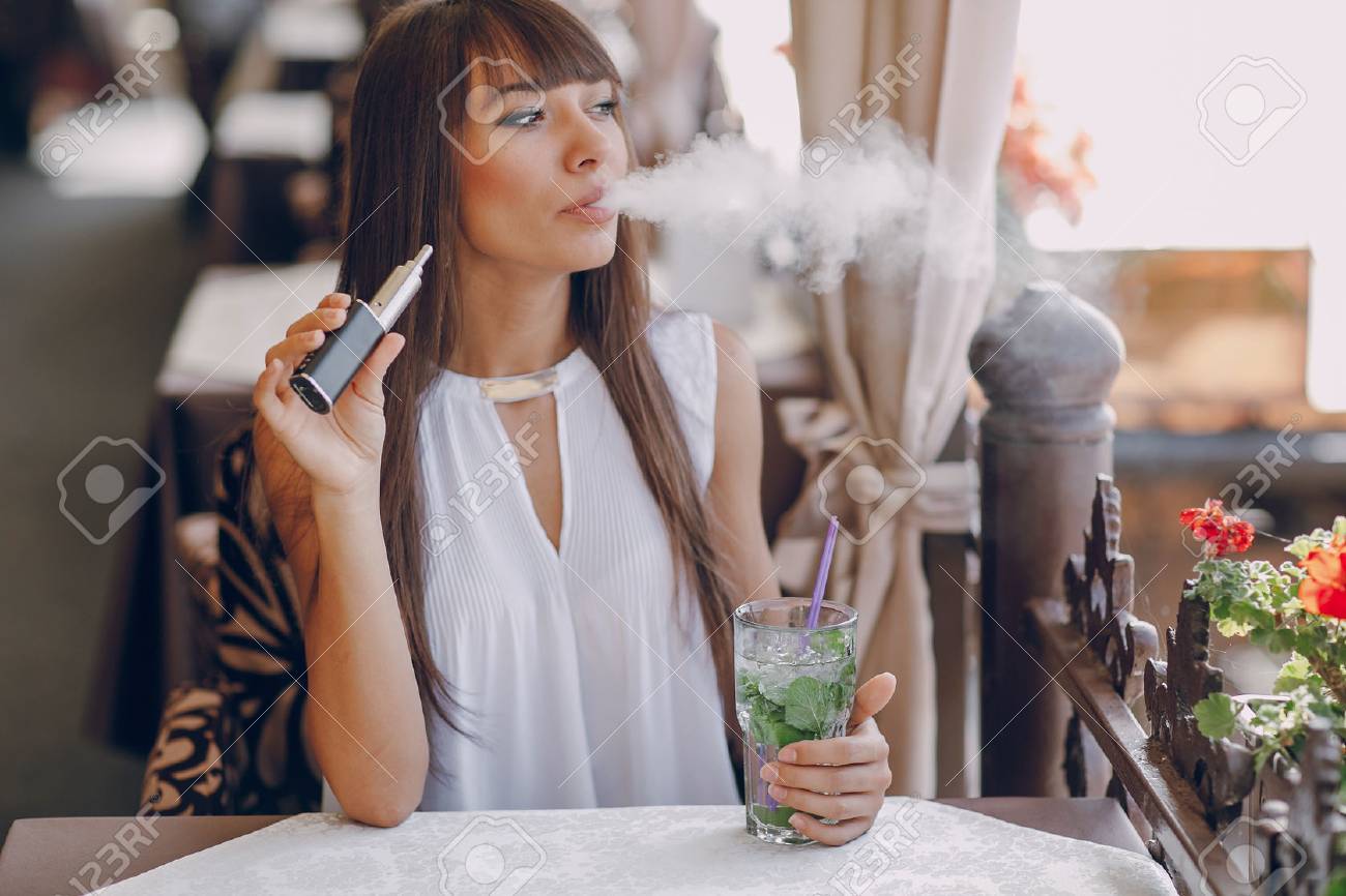 beautiful brunette smoke electronic cigarette on the summer terrace of restaurant - 54512613 beautiful brunette smoke electronic cigarette on the summer terrace of restaurant - 54512613