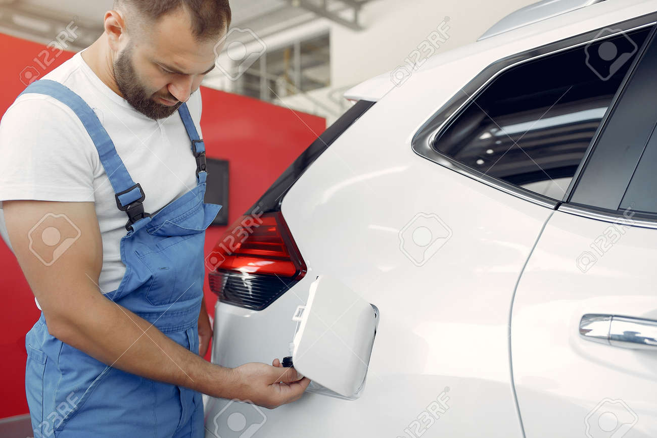 Handsome man in a blue uniform checks the car - 152143873 Handsome man in a blue uniform checks the car - 152143873