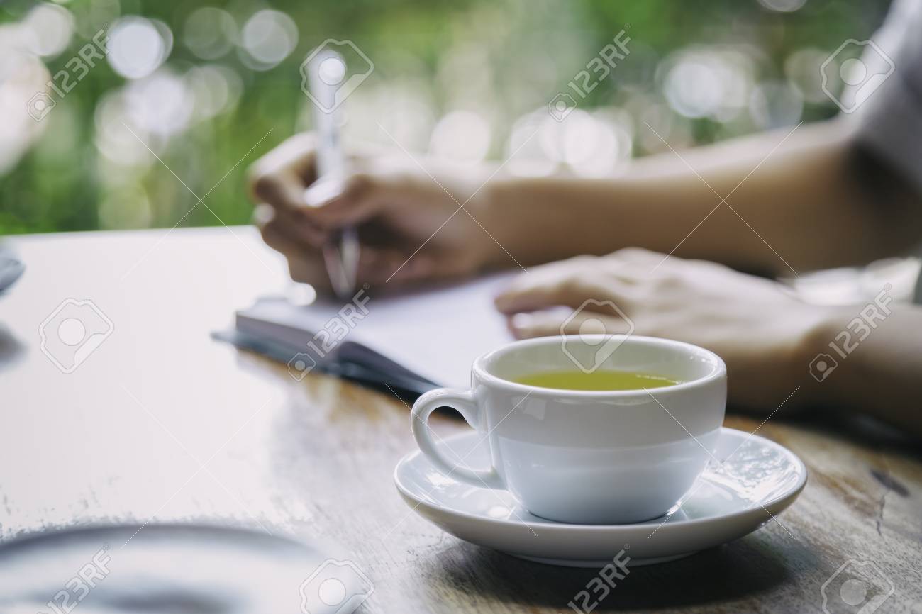 cup of tea with background of woman writing - 43281104 cup of tea with background of woman writing - 43281104