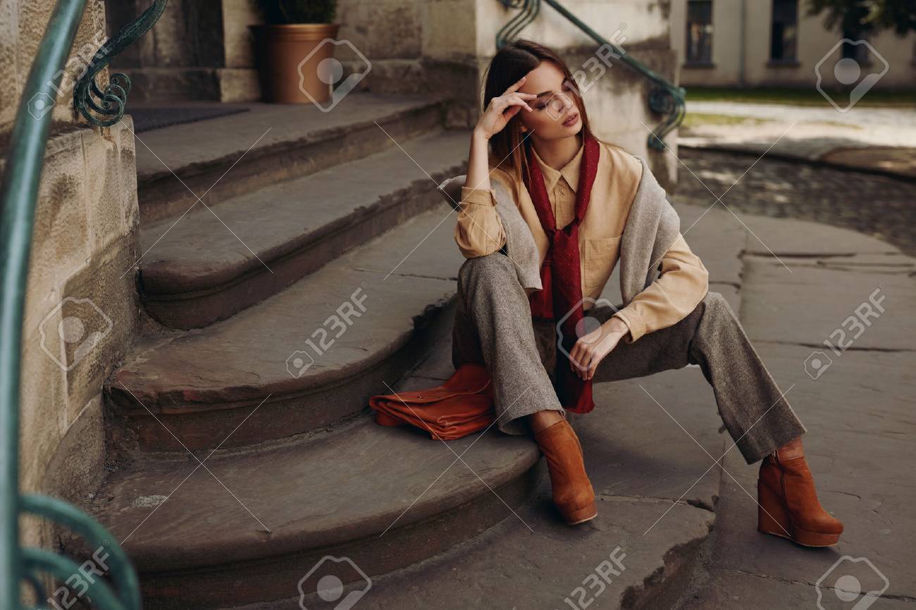 ストリートのファッション モデル スタイリッシュなおしゃれな秋服で美しいセクシーな女性 シャツ スカーフ パンツ セーター 靴春で階段に座っています ファッション性の高い秋服屋外でポーズの女の子 の写真素材 画像素材 Image