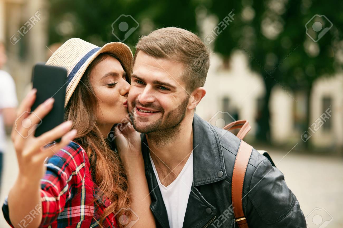 lovely tourist couple taking photos on phone portrait of young