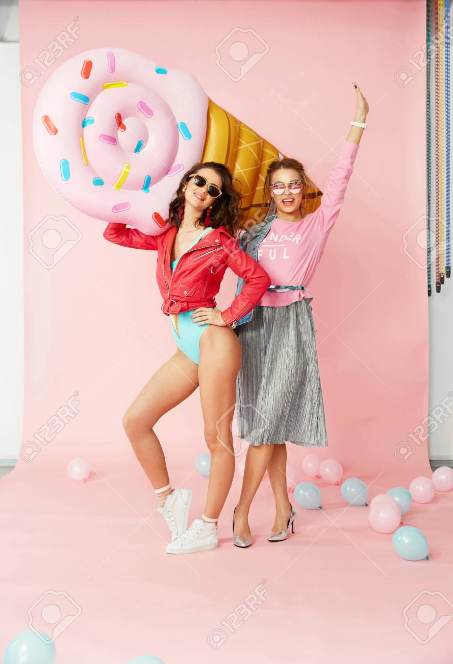 Fashion Women. Happy Friends In Summer Clothes. Beautiful Smiling Girls In Stylish  Wear Having Fun And Laughing, Holding Big Inflatable Ice Cream On Colorful  Background Indoors. High Quality Image. Stock Photo, Picture