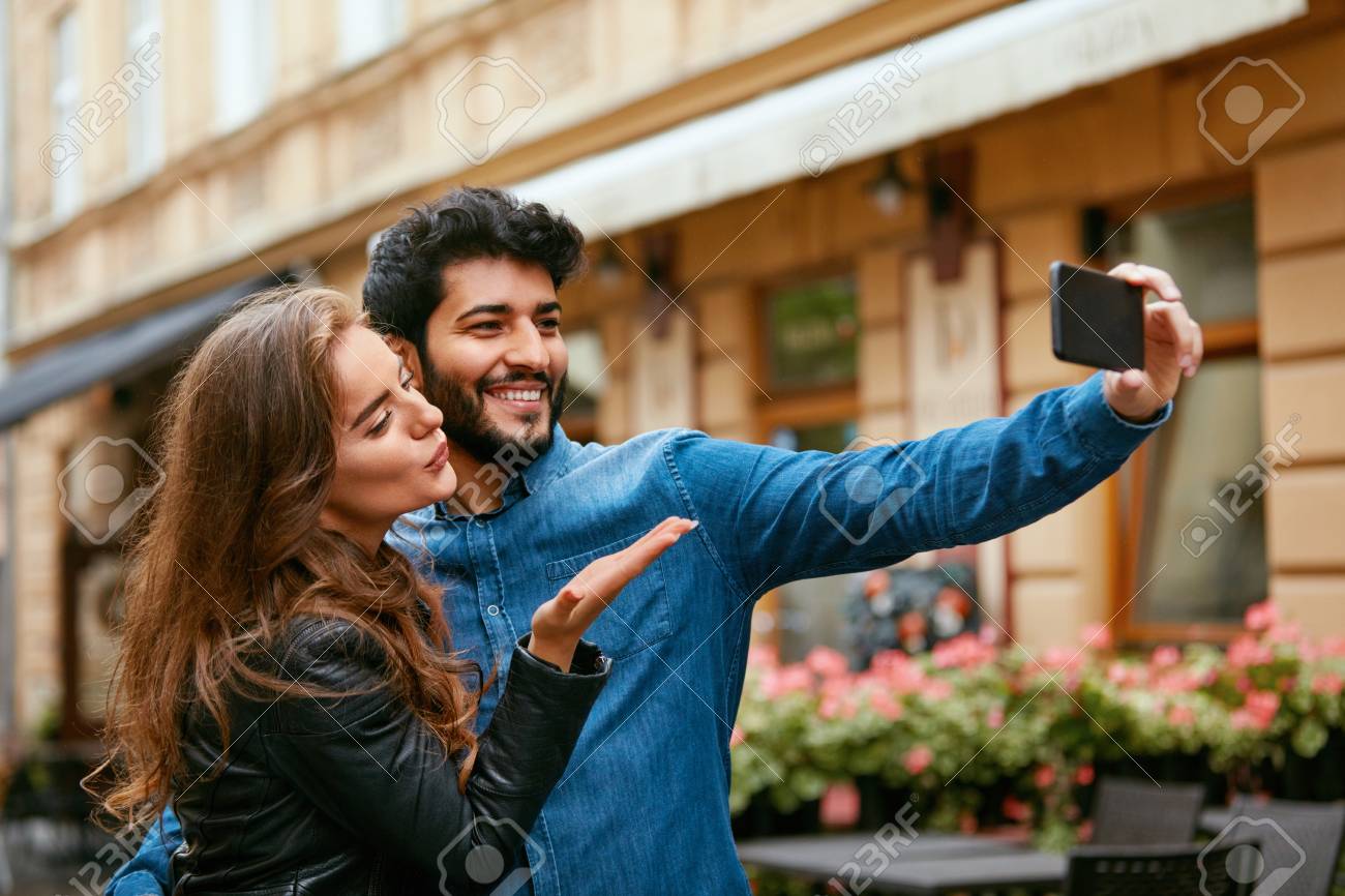 通りで電話を使うカップル 写真やビデオ通話を取って幸せな笑顔の人々 高解像度 の写真素材 画像素材 Image