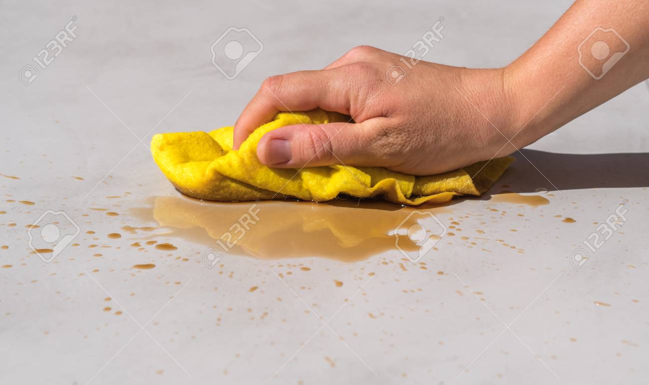 womans hand cleaning tea stain or spilled coffee on a cement floor with a yellow floor cloth dishcloth closeup - 87331717 womans hand cleaning tea stain or spilled coffee on a cement floor with a yellow floor cloth dishcloth closeup - 87331717