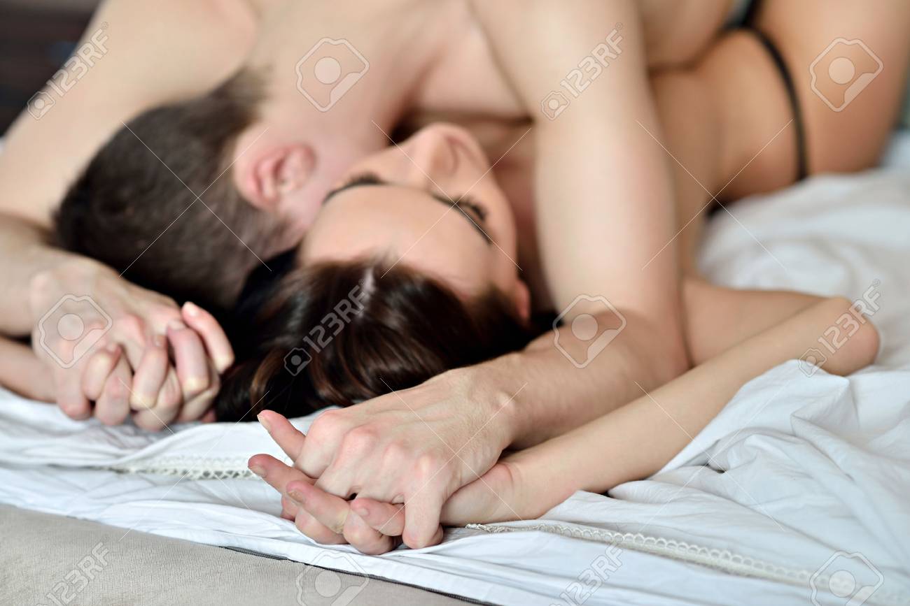 Young Sexy Couple On The Bed. Beautiful Lady And Guy In Erotic Pose.  Portrait Of Girl And Boy Indoors. Beauty Woman With Attractive Body In Lace  Lingerie. Closeup Naked Female And Male