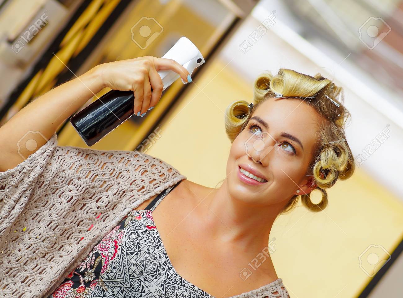 ぼやけた背景で 美容院でヘアスプレーでヘアスタイルを固定する若いブロンドの女性のクローズアップ の写真素材 画像素材 Image
