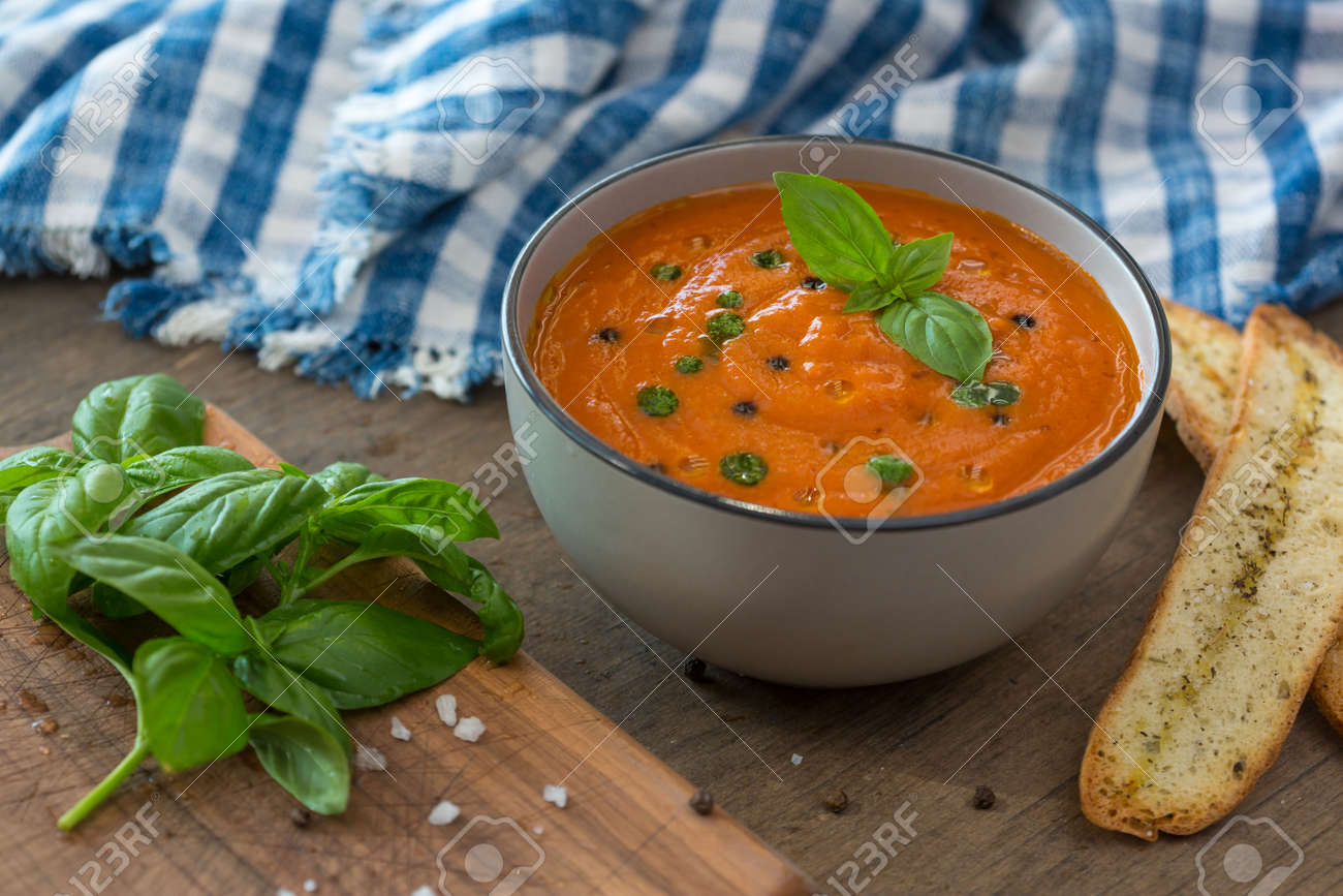 A bowl of fresh tomato soup in white ceramic bowl, garnished with basil, croutons, seasoning and a drizzle of olive oil, and served with crusty bread - 150727499 A bowl of fresh tomato soup in white ceramic bowl, garnished with basil, croutons, seasoning and a drizzle of olive oil, and served with crusty bread - 150727499