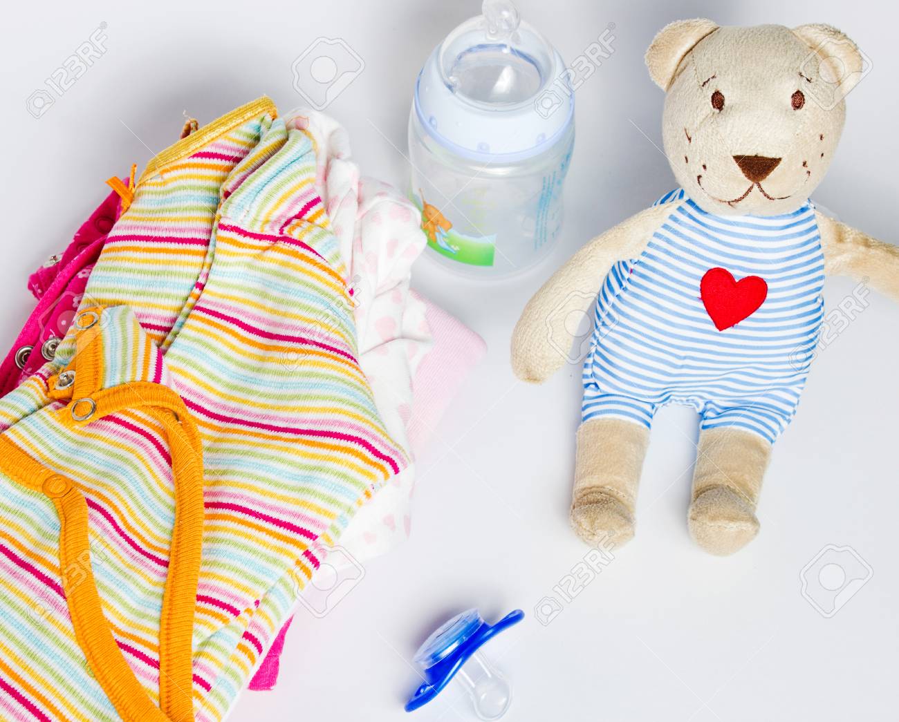 Una Pila Ropa Para Niños, Juguetes, Chupetes Sobre Un Fondo Blanco. Preparación Para La El Hacer Compras Para El Bebé. Fotos, Retratos, Imágenes Y Fotografía De Archivo Libres De Derecho.