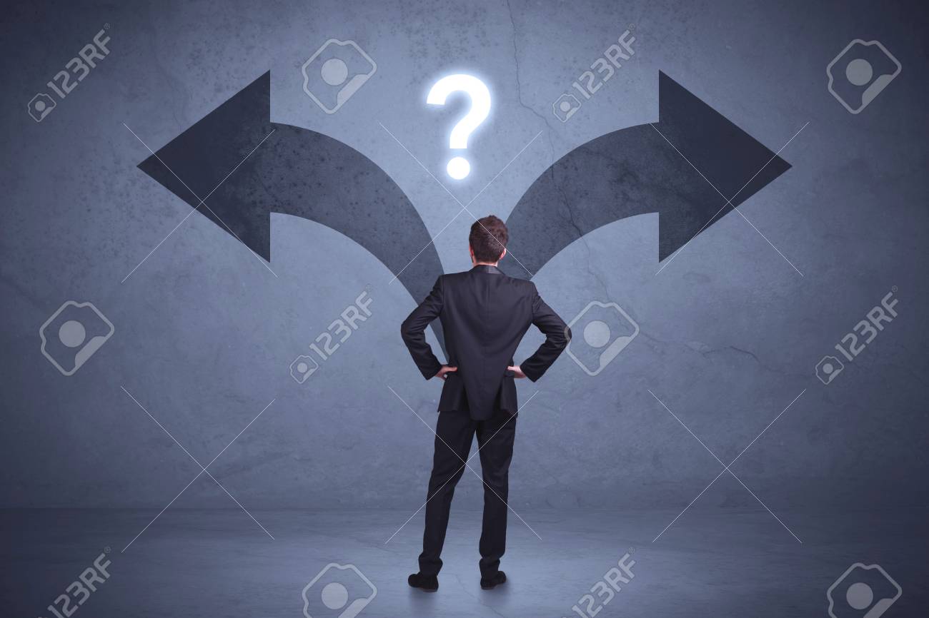 Businessman taking a decision while looking at arrows on the wall concept background - 96750373 Businessman taking a decision while looking at arrows on the wall concept background - 96750373