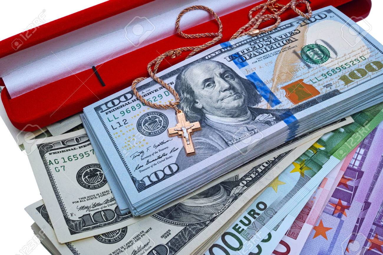 gold cross on a stack of dollars and euros the quality of medium