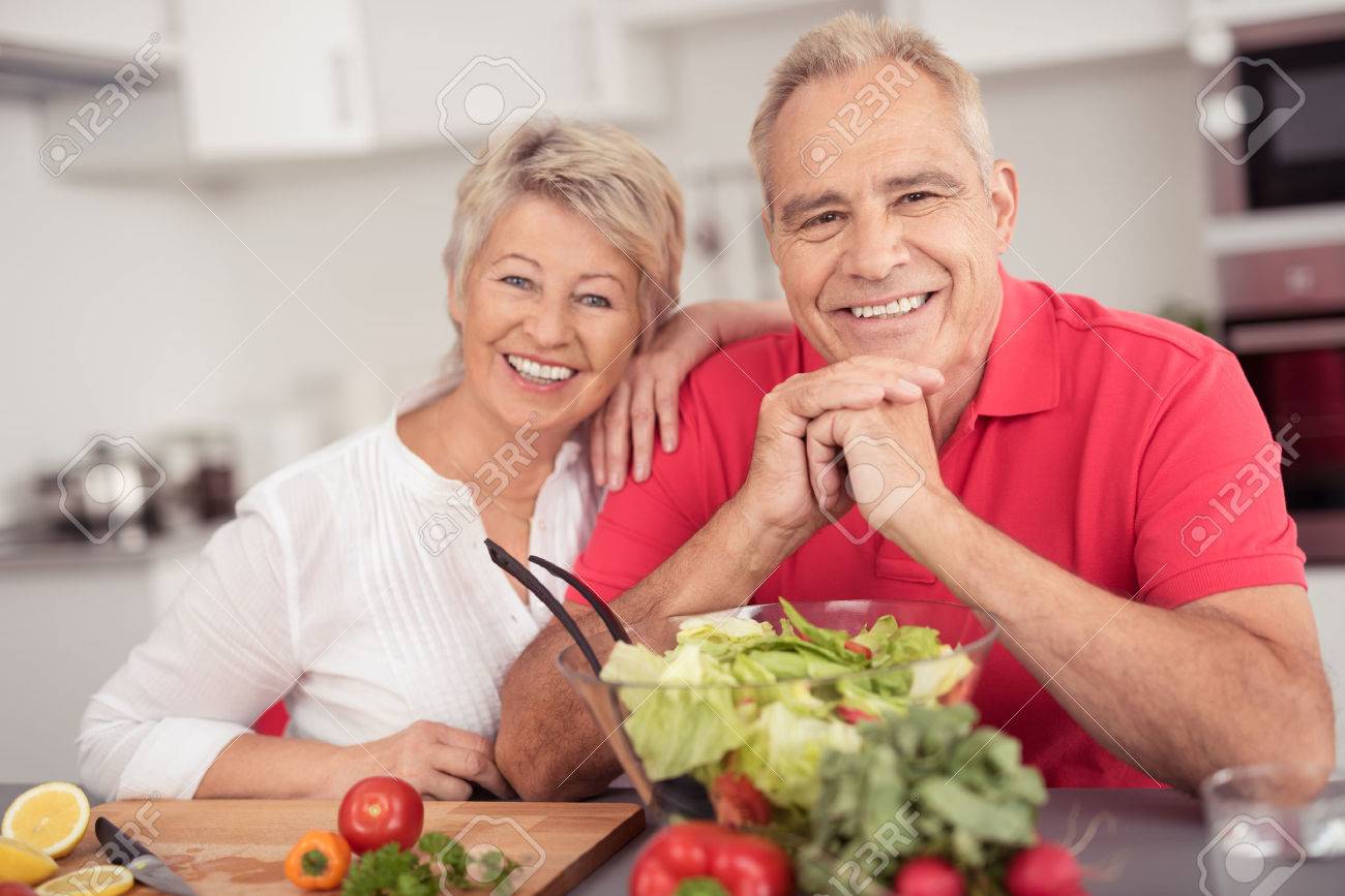 Portrait of a Happy Senior Couple Sitting at the Kitchen Table with a Bowl of Fresh Salad, Smiling at the Camera. - 41689893 Portrait of a Happy Senior Couple Sitting at the Kitchen Table with a Bowl of Fresh Salad, Smiling at the Camera. - 41689893
