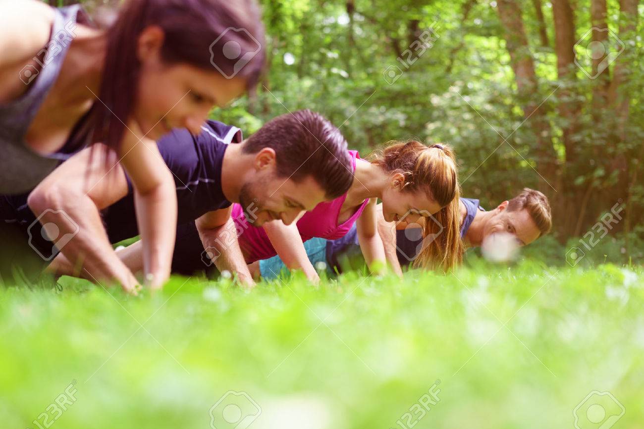 Four young people doing push-ups in a park during a fitness workout viewed very low angle across the grass - 59886791 Four young people doing push-ups in a park during a fitness workout viewed very low angle across the grass - 59886791