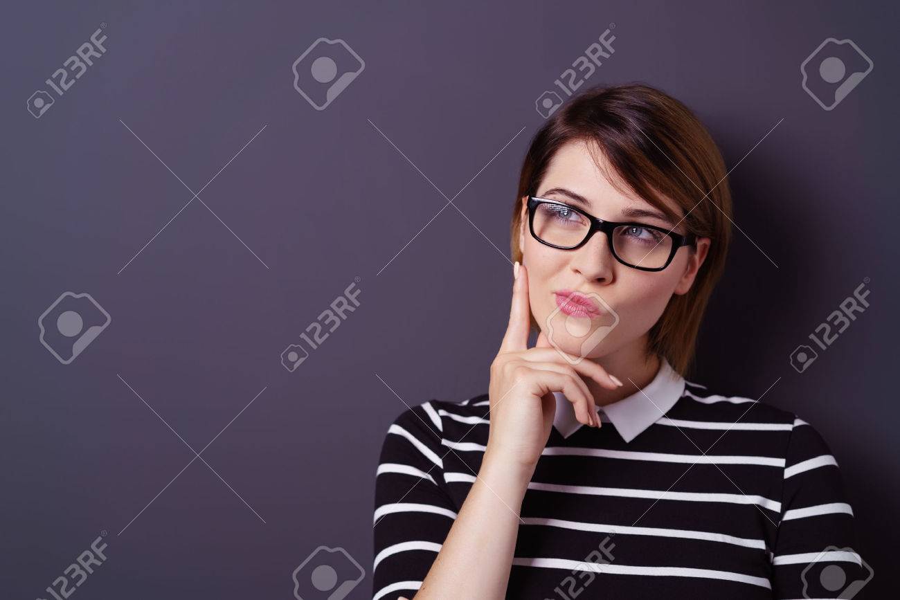 Single young attractive thinking woman with fingers on chin and short hair over dark background - 63969781 Single young attractive thinking woman with fingers on chin and short hair over dark background - 63969781