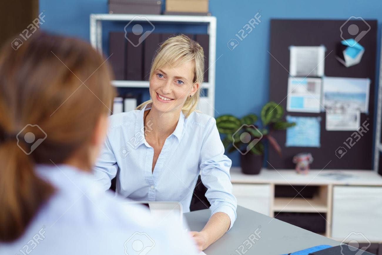 Attractive young woman in a business interview for a job vacancy listening attentively to the female interviewer with a smile, over the shoulder view - 63969825 Attractive young woman in a business interview for a job vacancy listening attentively to the female interviewer with a smile, over the shoulder view - 63969825