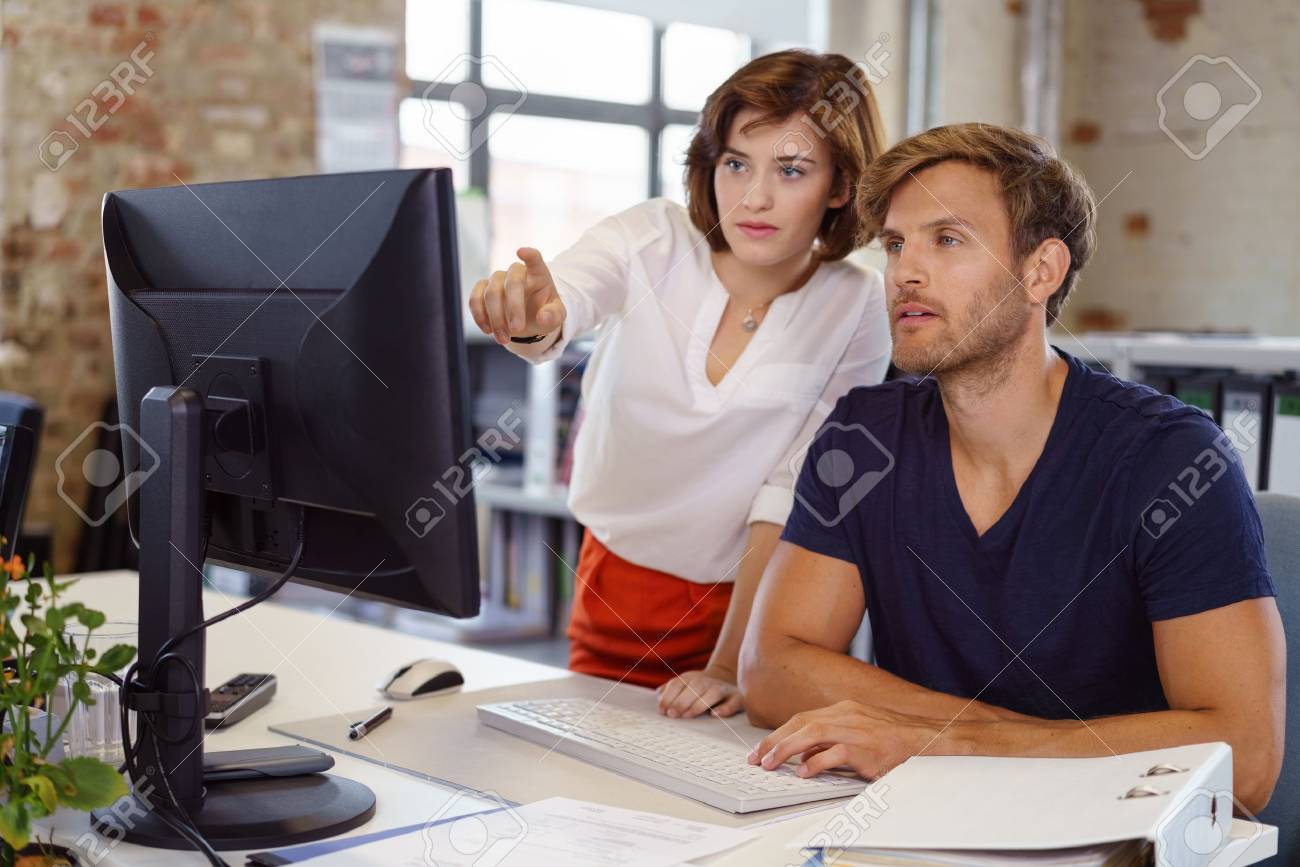Woman showing something to young man colleague pointing her finger to computer screen, both looking at monitor - 70547138 Woman showing something to young man colleague pointing her finger to computer screen, both looking at monitor - 70547138