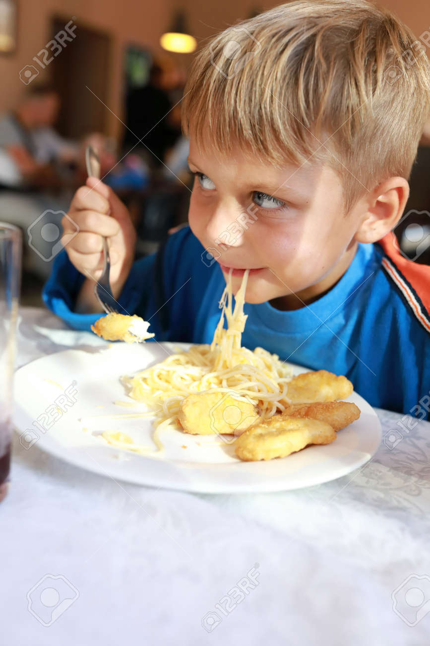 Child eating spaghetti with nuggets in restaurant - 155372755 Child eating spaghetti with nuggets in restaurant - 155372755