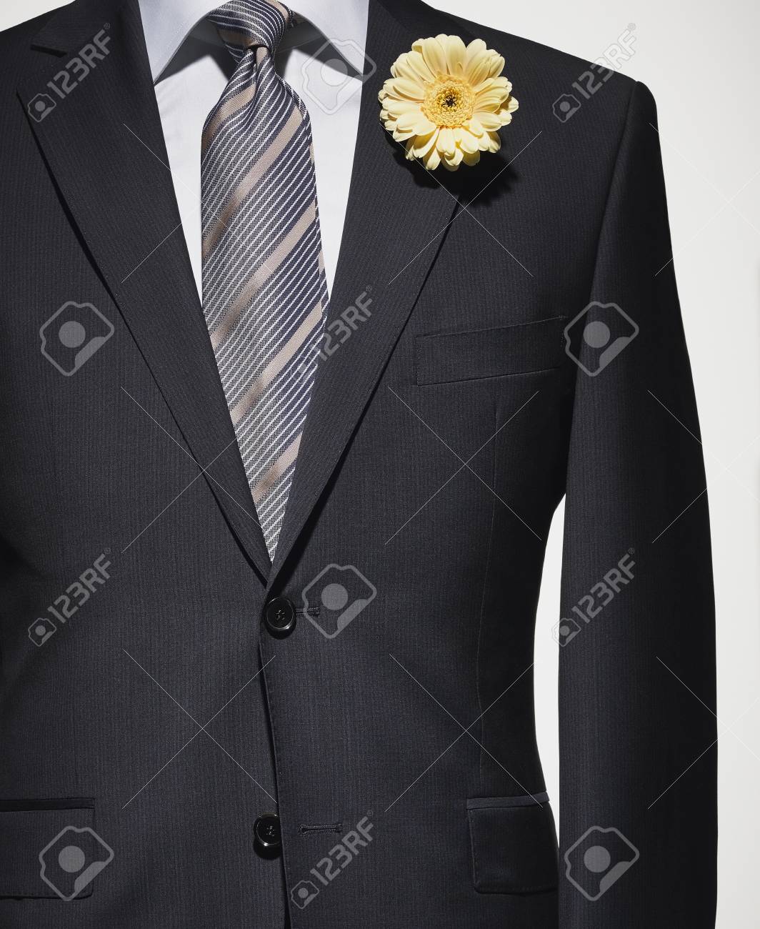 Détail Dune Veste De Costume Bleu Foncé Avec Chemise Grise Et Cravate à Rayures Et Fleur Jaune