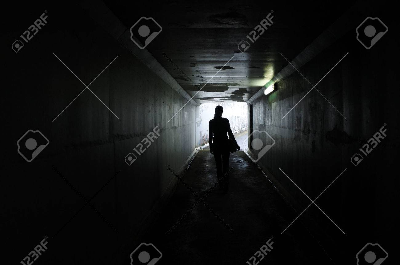 Silhouette of a young woman walks alone in a dark tunnel. Violence against women concept. Real people, copy space - 62168823 Silhouette of a young woman walks alone in a dark tunnel. Violence against women concept. Real people, copy space - 62168823