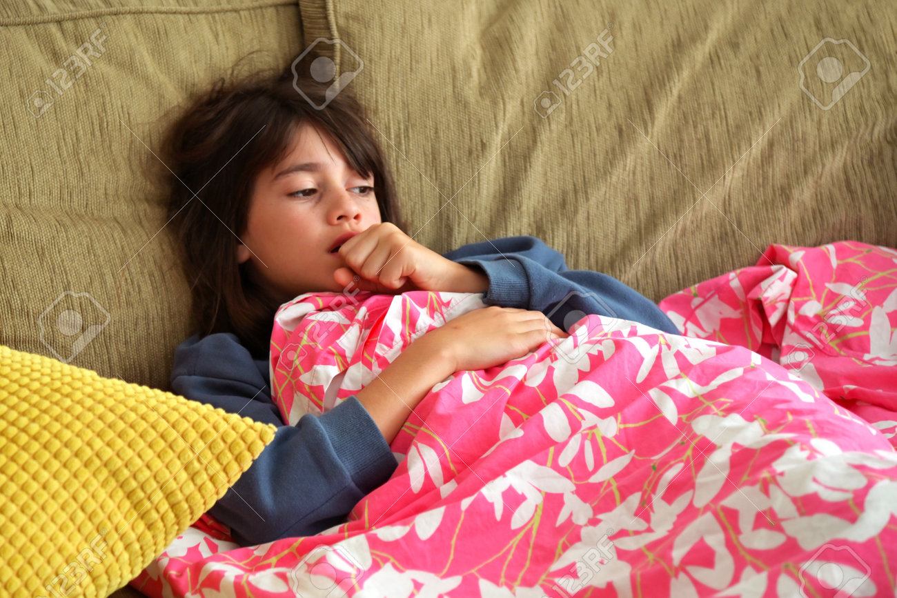 Young sick girl (female age 10-11) covered with blanket is coughing. - 168379474 Young sick girl (female age 10-11) covered with blanket is coughing. - 168379474