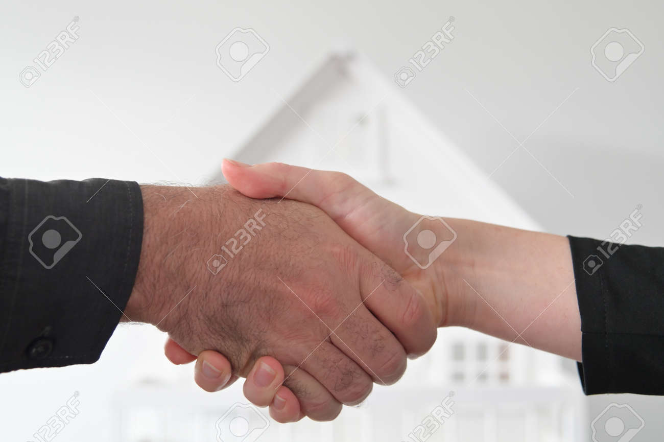 Two people (male and female) are shaking hands against a white house. Mortgage, housing market, home loans and property, management concept. No people. Copy space - 169904662 Two people (male and female) are shaking hands against a white house. Mortgage, housing market, home loans and property, management concept. No people. Copy space - 169904662