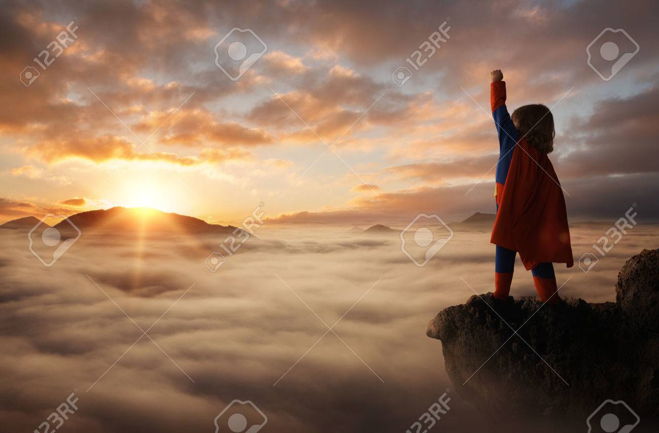 Little boy acting like a superhero on top of the mountain at sunset with copy space - 72765273 Little boy acting like a superhero on top of the mountain at sunset with copy space - 72765273