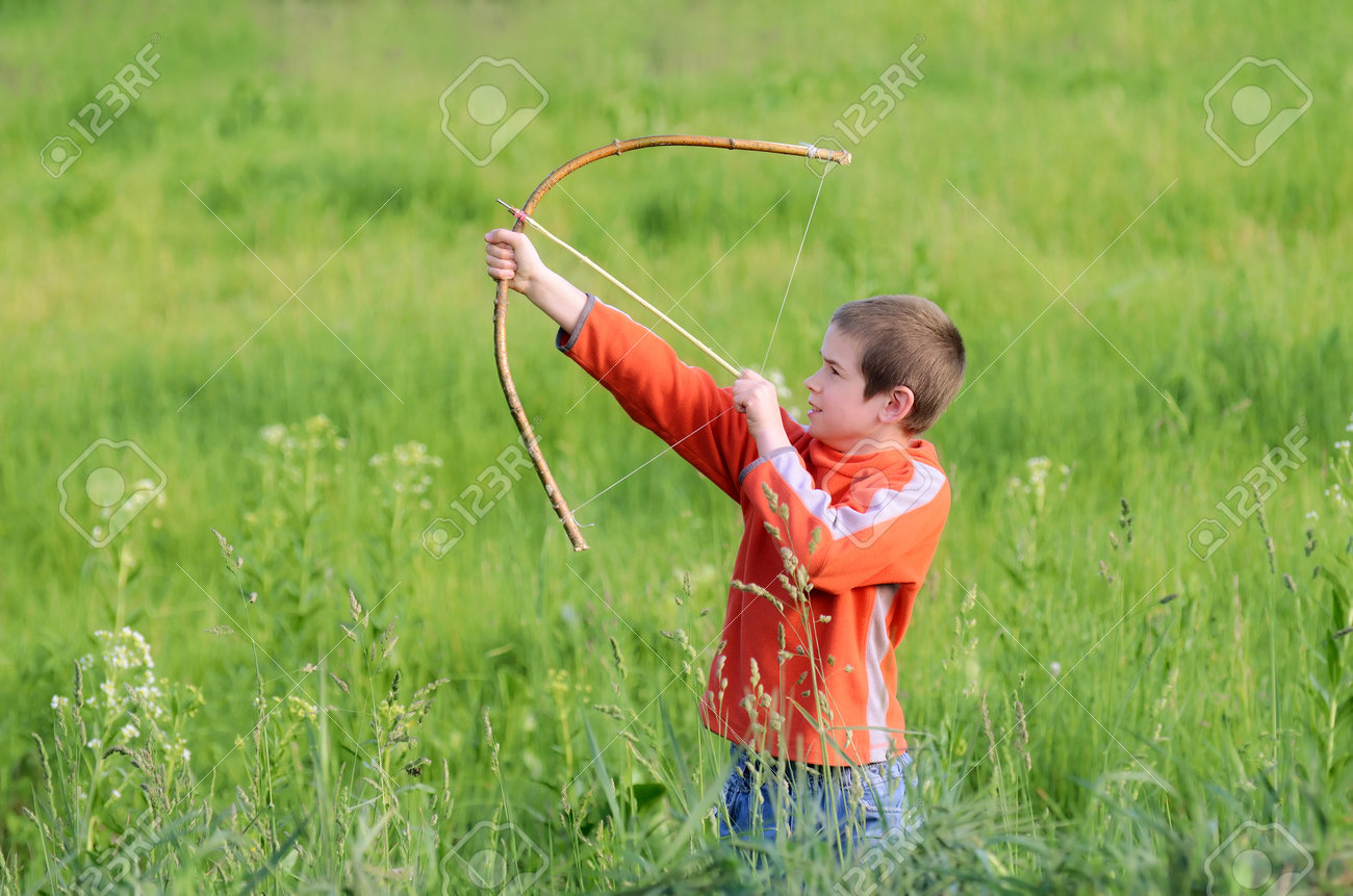 Little boy is playing with hand-made bow in the countryside - 93925111 Little boy is playing with hand-made bow in the countryside - 93925111