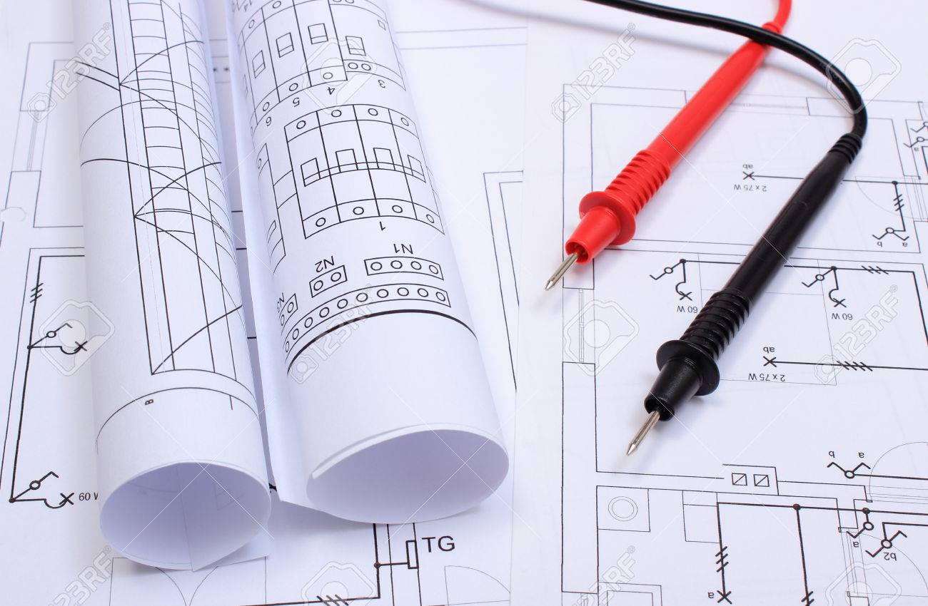 rolls of electrical diagrams and cables of multimeter lying on construction drawing of house drawings rolls of electrical diagrams and cables of multimeter lying on construction drawing of house drawings