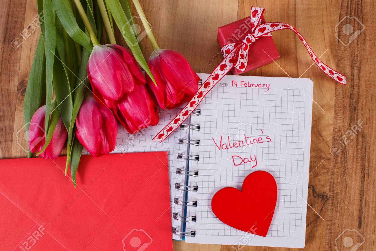 2 月 14 日ノートやカレンダー 新鮮なチューリップで書かれた封筒 ラップされたギフト バレンタインの日の装飾の木の心に愛の手紙の日付 の写真素材 画像素材 Image