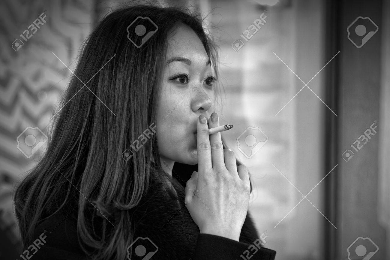 Black and white photo of an asian woman smoking in real life stock photo