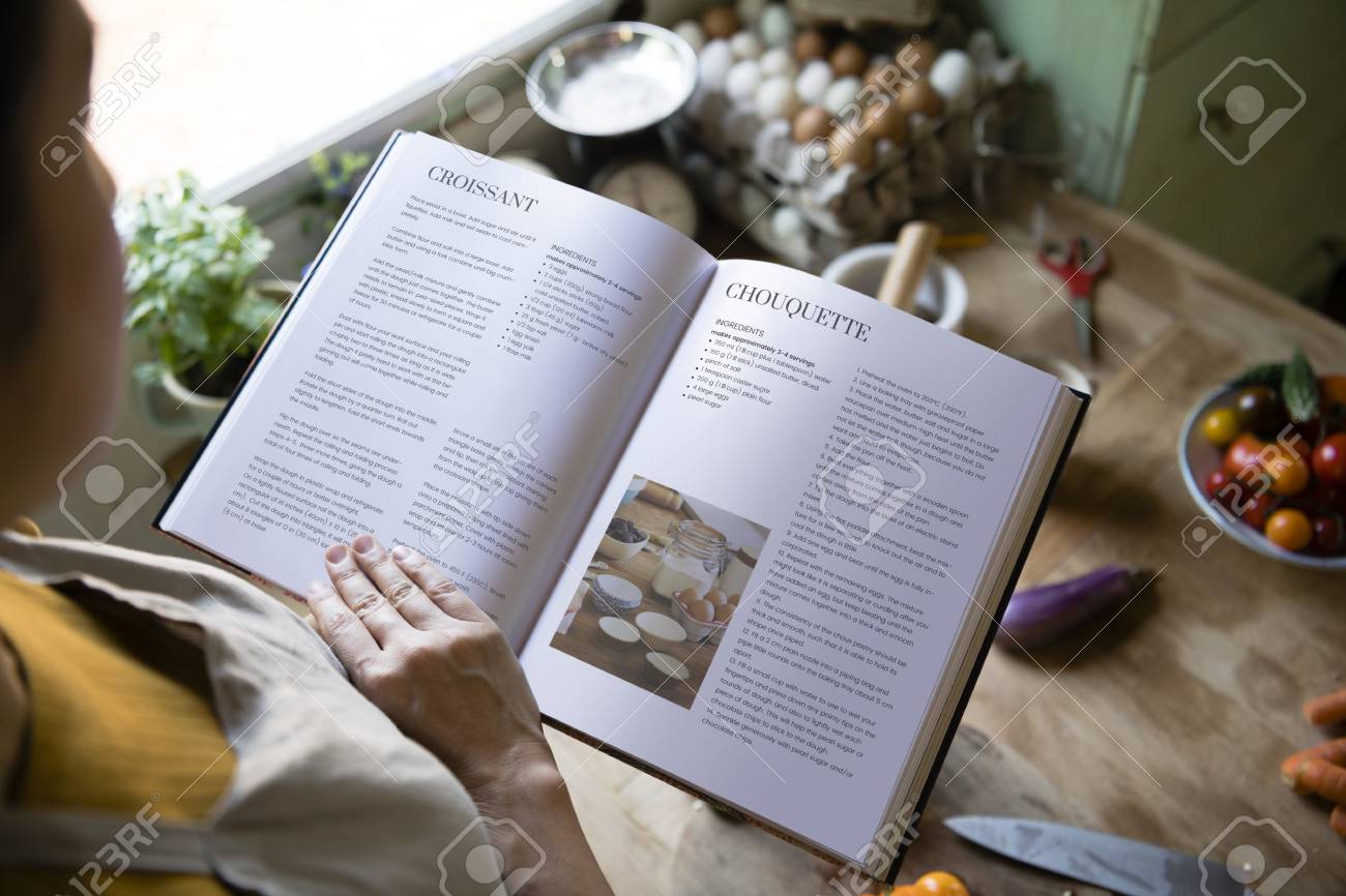 Happy woman reading a cookbook in the kitchen - 111840820 Happy woman reading a cookbook in the kitchen - 111840820