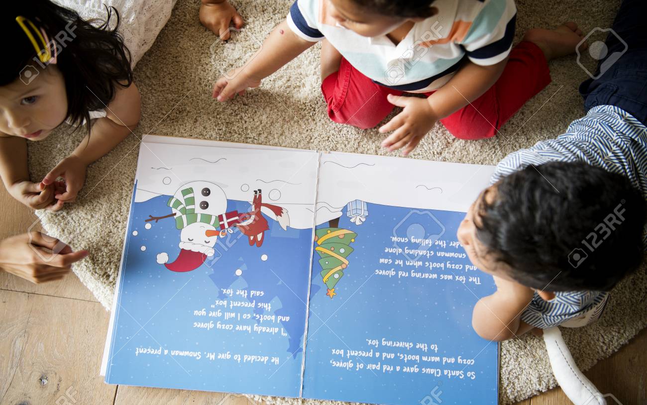 Young kids reading a Christmas story together - 113891372 Young kids reading a Christmas story together - 113891372